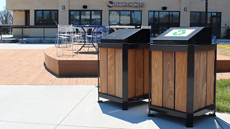 Lofty trash and recycle receptacles site near an outdoor dining area